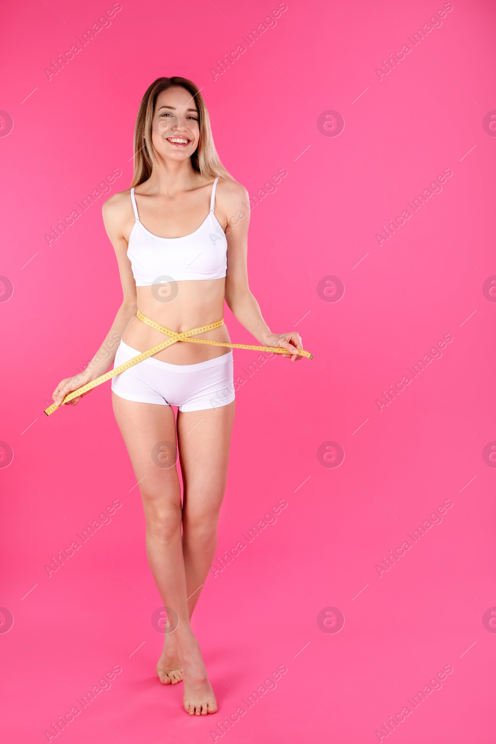 Photo of Slim woman measuring her waist on color background, space for text. Perfect body