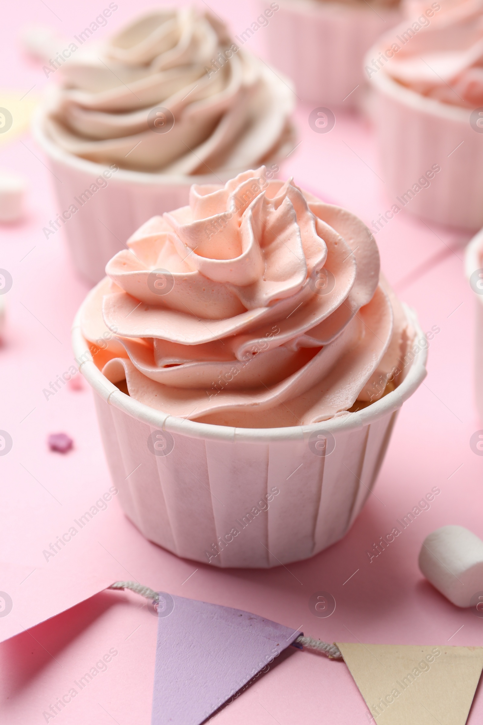 Photo of Delicious birthday cupcakes and bunting flags on pink background, closeup