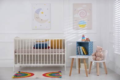 Cute baby room interior with comfortable crib and pictures