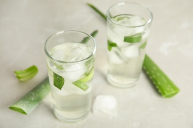 Photo of Fresh aloe drink in glasses and leaves on light table