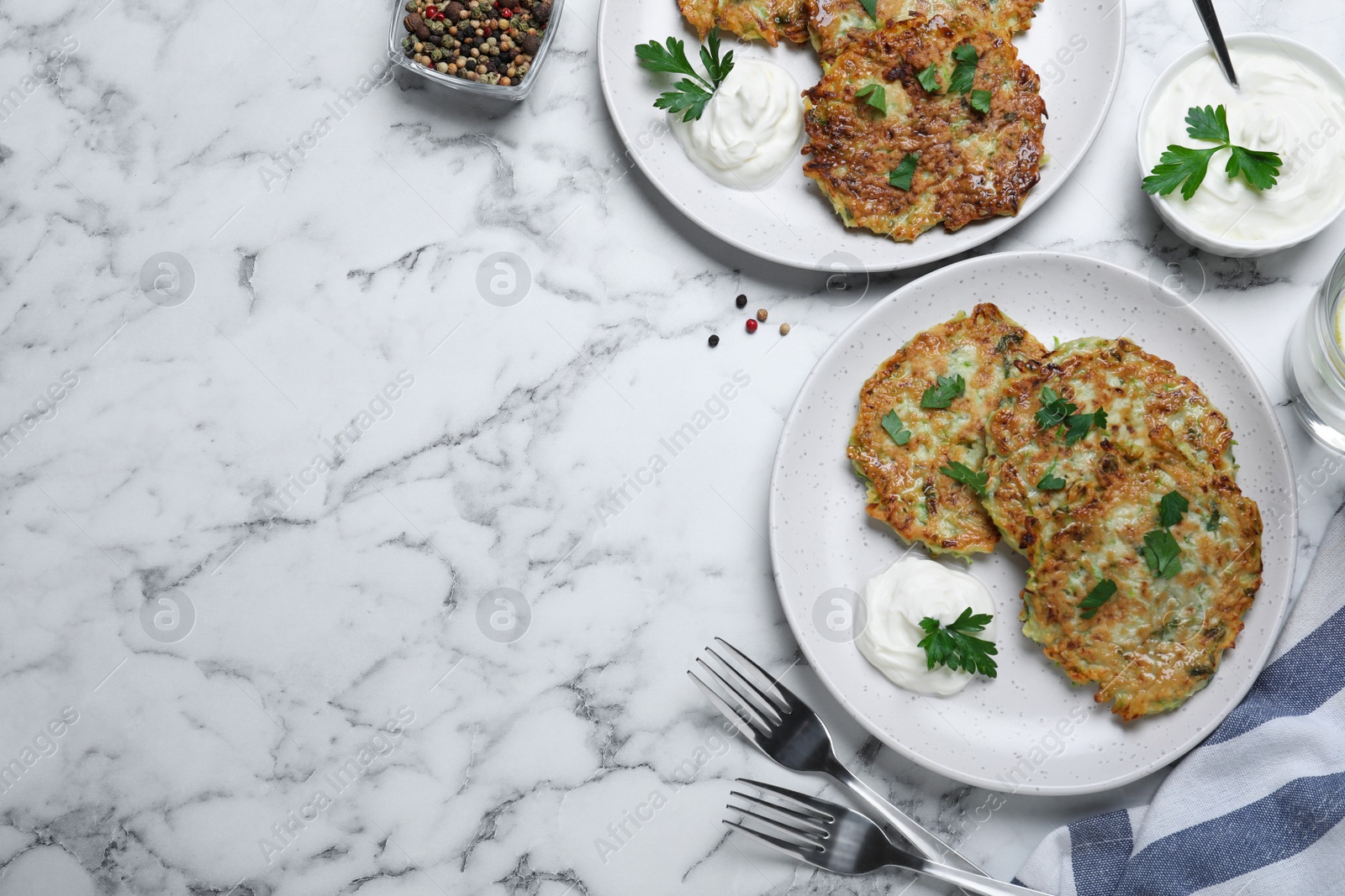 Photo of Delicious zucchini fritters served on white marble table, flat lay. Space for text