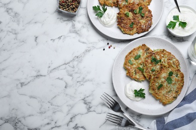 Delicious zucchini fritters served on white marble table, flat lay. Space for text