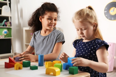 Photo of Cute little children playing with building blocks in kindergarten. Indoor activity