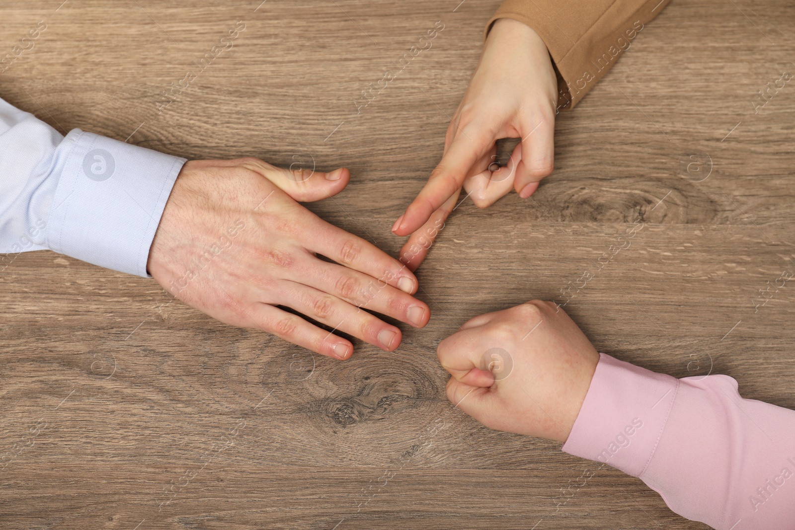 Photo of Closeup of people playing rock, paper and scissors on wooden background, top view