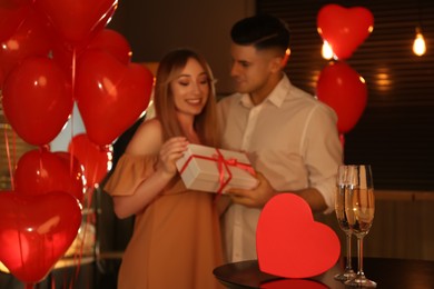 Photo of Lovely couple with gift in room. Valentine's day celebration