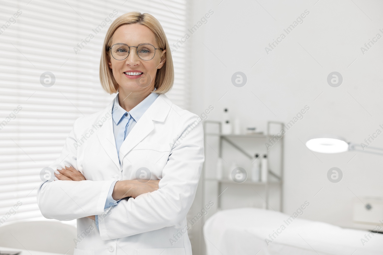 Photo of Portrait of happy dermatologist in modern clinic, space for text