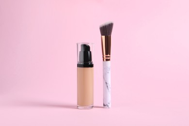 Photo of Bottle of skin foundation and brush on pink background. Makeup product