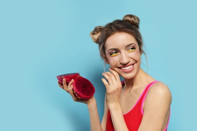 Young woman with fresh pitahaya on light blue background, space for text. Exotic fruit