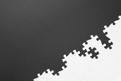 Photo of Blank white puzzle pieces on black background, flat lay. Space for text