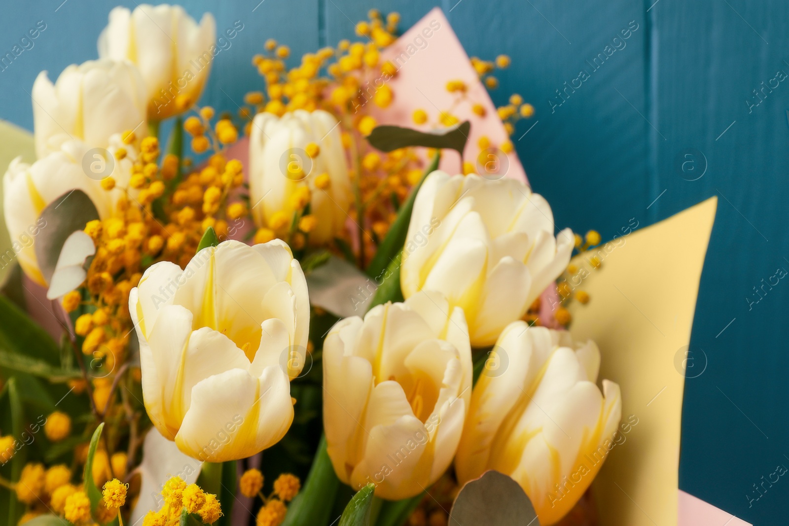 Photo of Bouquet of beautiful spring flowers near turquoise wooden wall, closeup