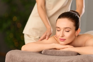 Photo of Beautiful young woman enjoying massage in spa salon