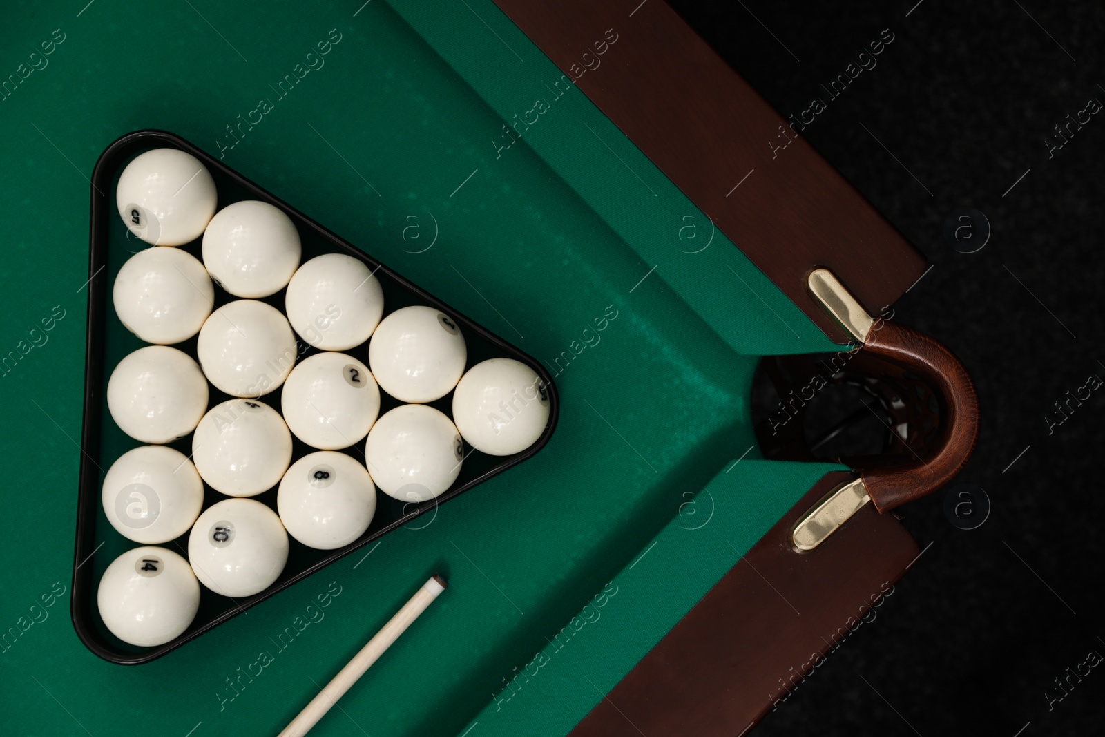 Photo of Billiard balls in triangle and cue on table, flat lay