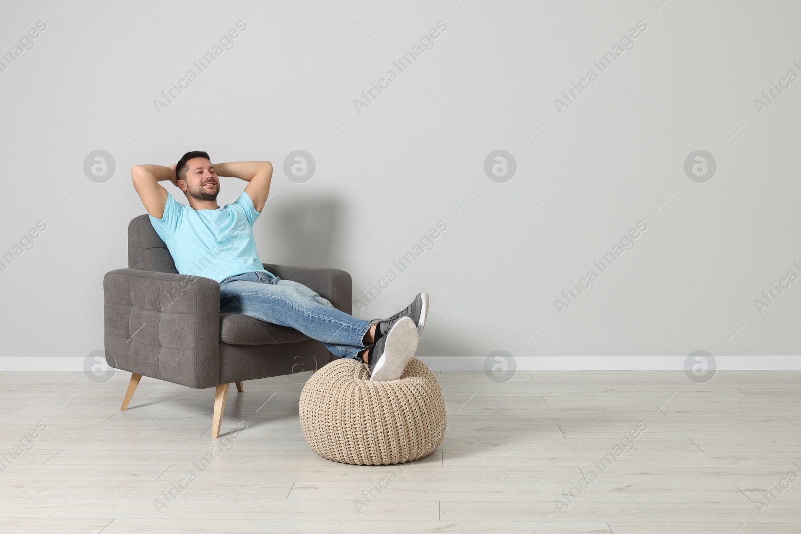 Photo of Happy man sitting in armchair indoors, space for text