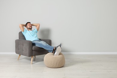 Happy man sitting in armchair indoors, space for text