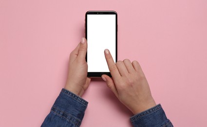 Woman using smartphone on pink background, top view