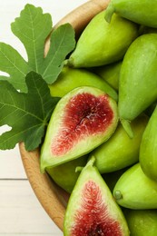 Cut and whole fresh green figs on white wooden table, top view