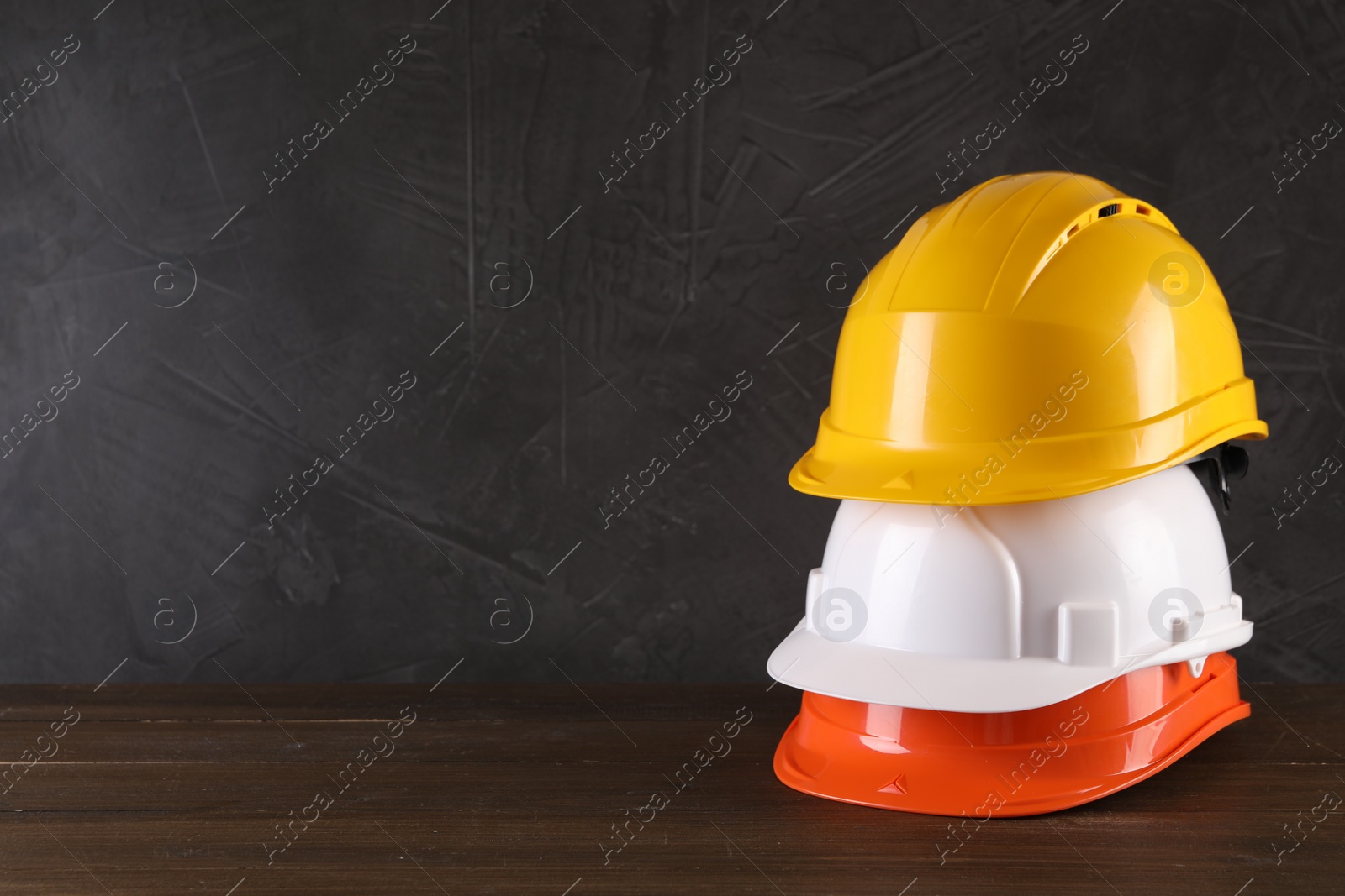 Photo of Hard hats on wooden table, space for text. Safety equipment