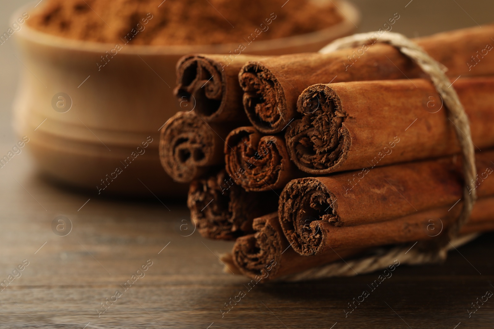 Photo of Dry aromatic cinnamon sticks on wooden table, closeup