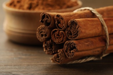 Photo of Dry aromatic cinnamon sticks on wooden table, closeup