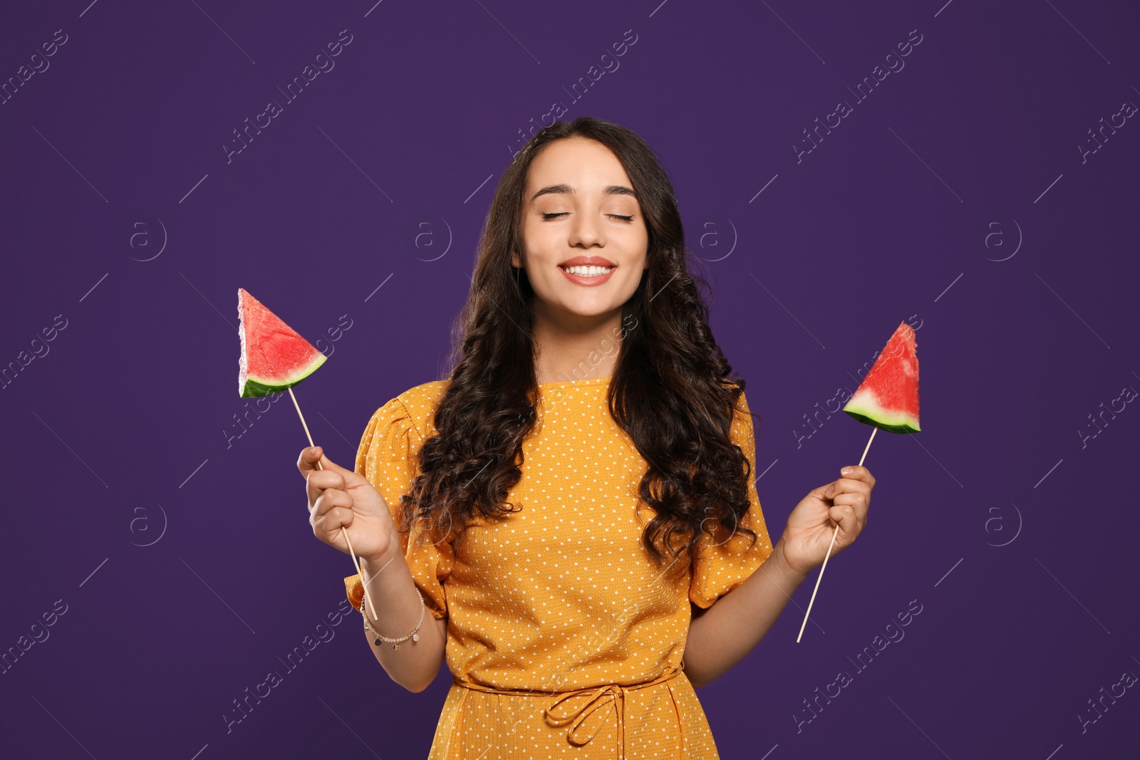 Photo of Beautiful young woman with pieces of watermelon on purple background