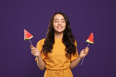 Photo of Beautiful young woman with pieces of watermelon on purple background