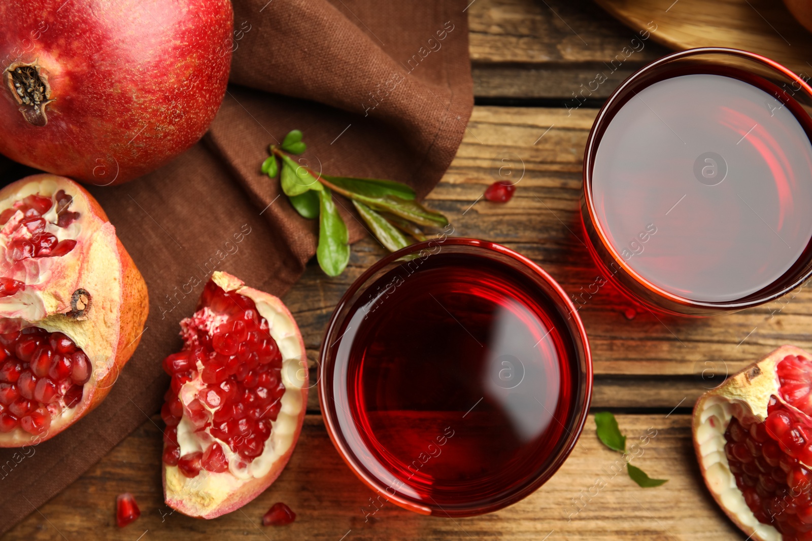 Photo of Glasses of pomegranate juice and fresh fruits on wooden table, flat lay