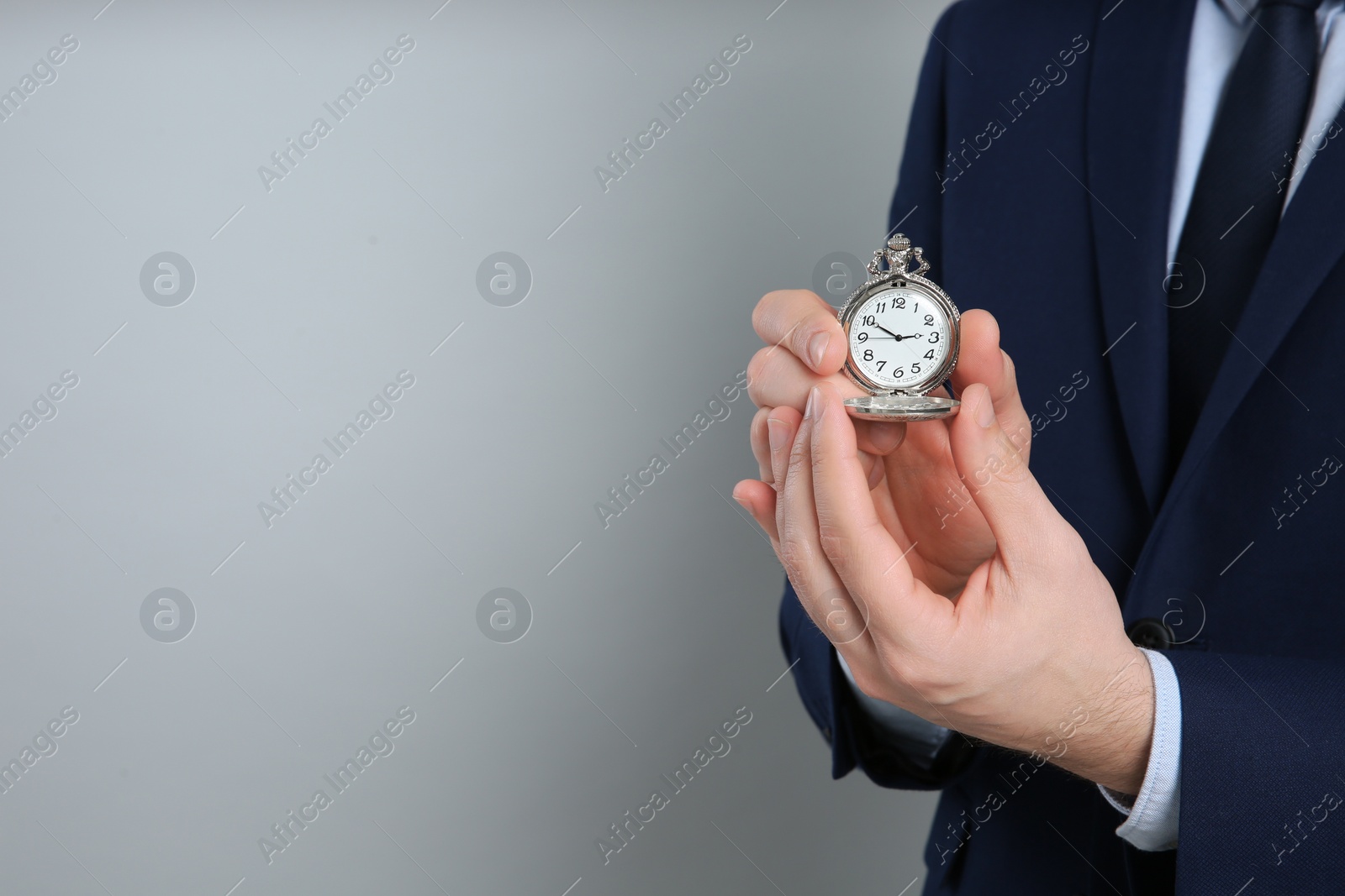 Photo of Closeup view of businessman holding pocket watch on grey background, space for text. Time management