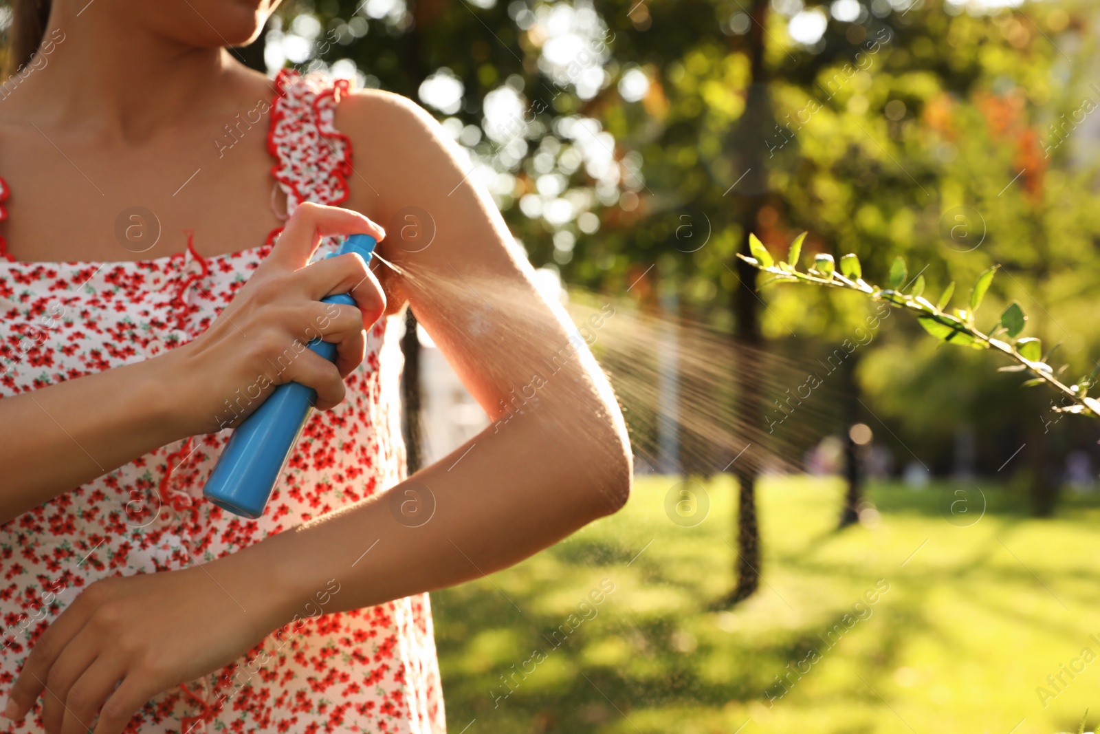 Photo of Woman applying insect repellent onto hand in park, closeup. Space for text