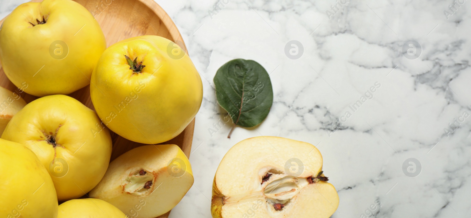 Image of Fresh ripe organic quinces with leaves on white marble table, flat lay with space for text. Banner design