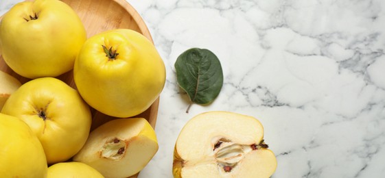 Image of Fresh ripe organic quinces with leaves on white marble table, flat lay with space for text. Banner design