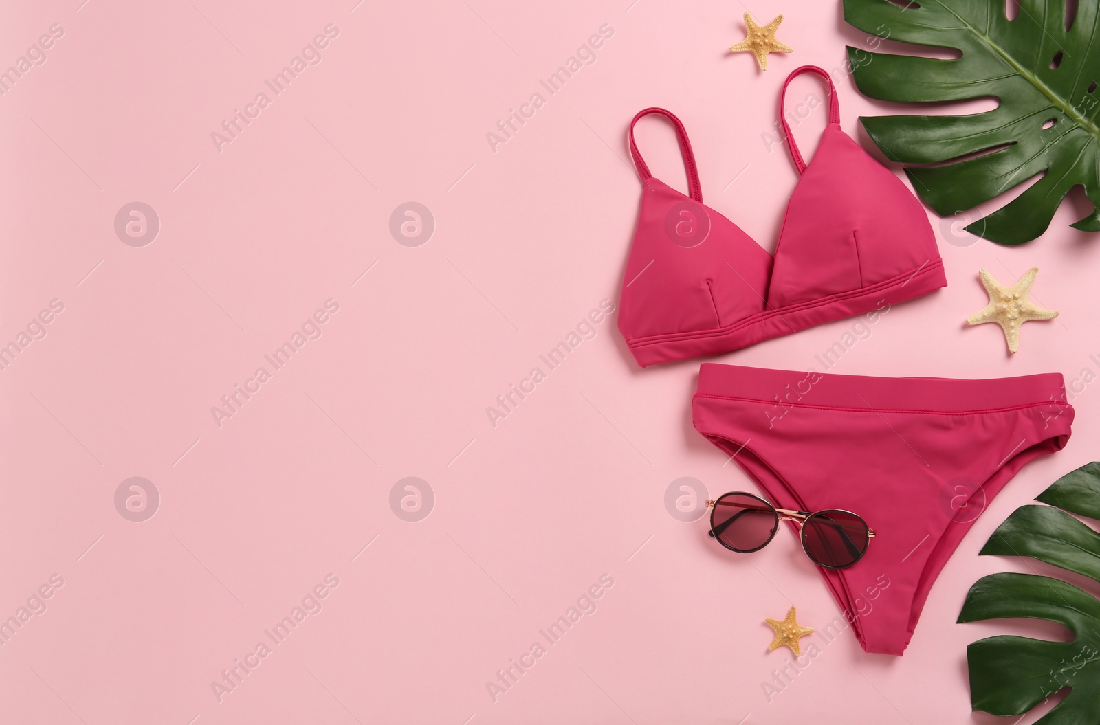 Photo of Stylish bikini and beach accessories on pink background, flat lay. Space for text