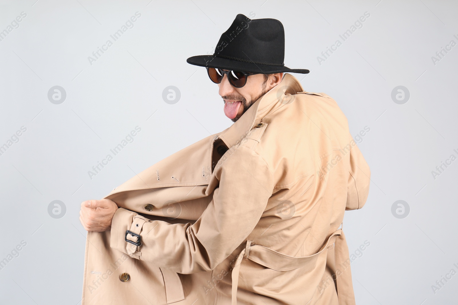 Photo of Exhibitionist exposing naked body under coat on light background