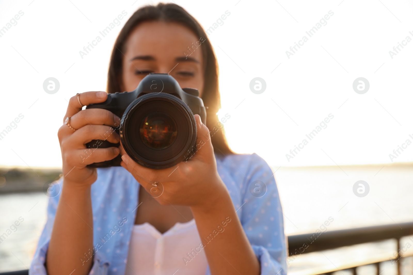 Photo of Young photographer taking picture with professional camera outdoors