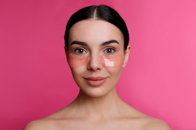 Photo of Beautiful young woman with under eye patches on pink background