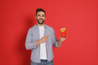 Man with French fries on red background