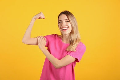Photo of Strong woman as symbol of girl power on yellow background. 8 March concept