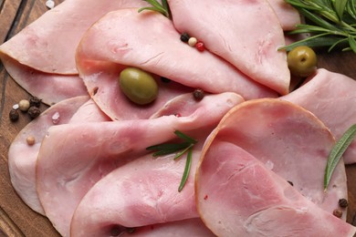 Photo of Slices of delicious ham with rosemary and olives on wooden board, flat lay