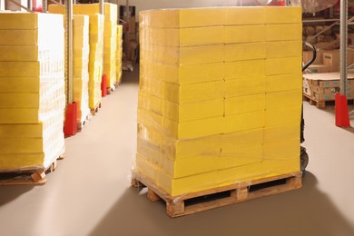 Photo of Manual pallet truck with stacked boxes in warehouse. Wholesaling