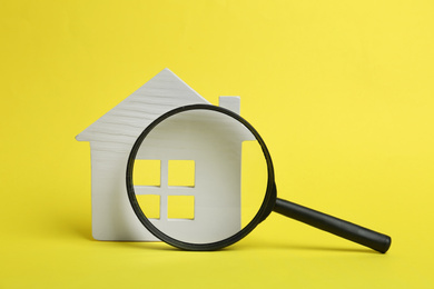 Photo of House model and magnifying glass on yellow background. Search concept