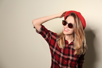 Photo of Young woman wearing stylish sunglasses on beige background. Space for text