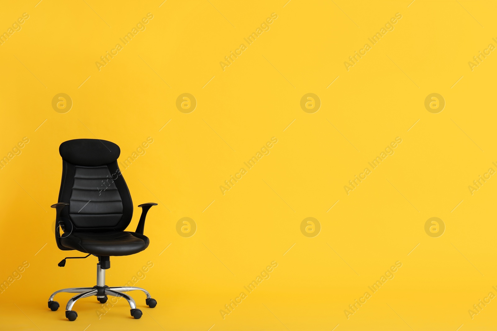 Photo of Modern office chair on yellow background. Space for text