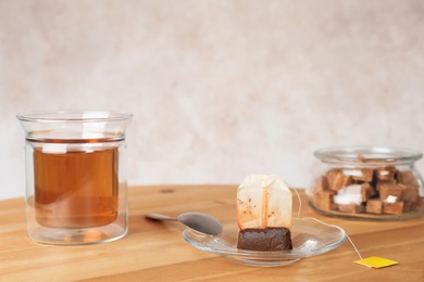 Photo of Saucer, spoon with used teabag and cup on table. Space for text