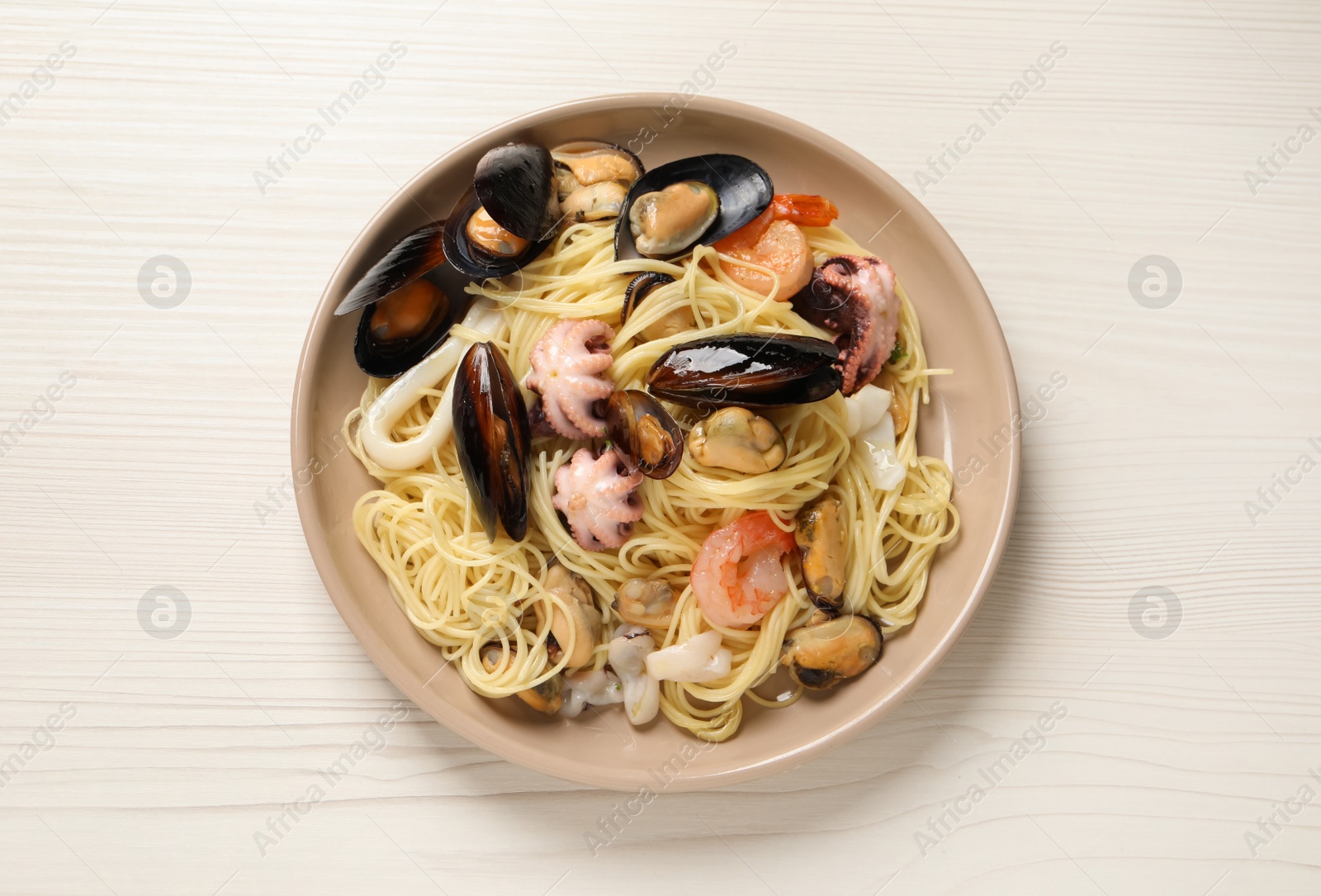 Photo of Delicious pasta with sea food on white wooden table, top view