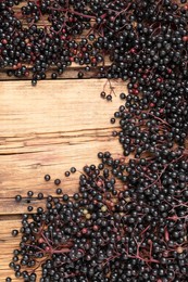 Photo of Elderberries (Sambucus) on wooden table, flat lay