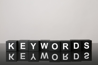 Photo of Black cubes with word KEYWORDS on light grey background