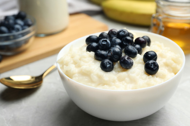 Delicious rice pudding with blueberries on marble table, closeup