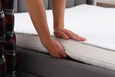 Man putting soft mattress on bed, closeup