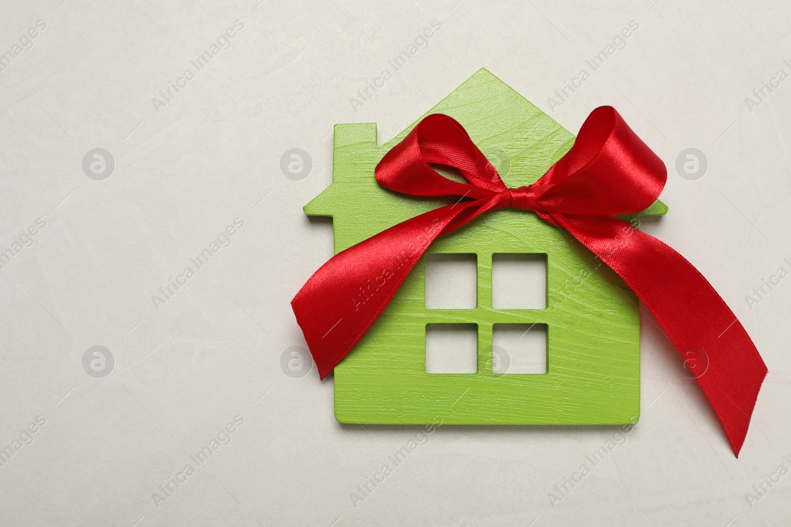 Photo of Wooden house model with red bow on white table, top view and space for text. Housewarming party