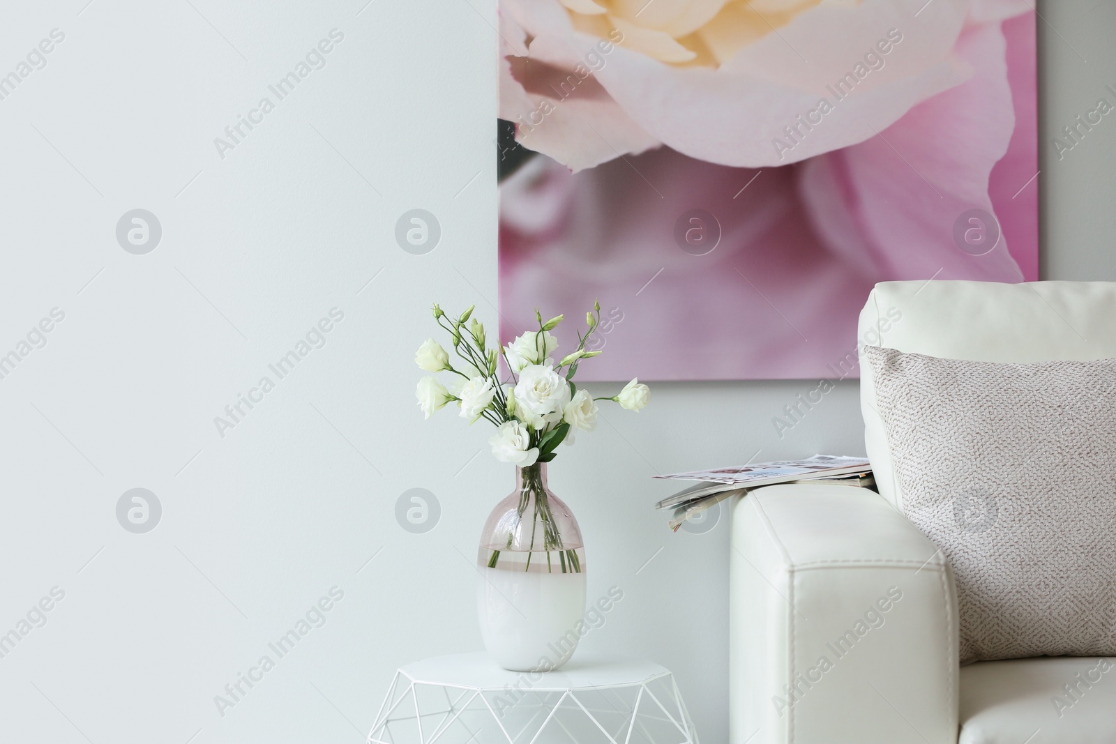 Photo of Vase with fresh flowers on white table in living room