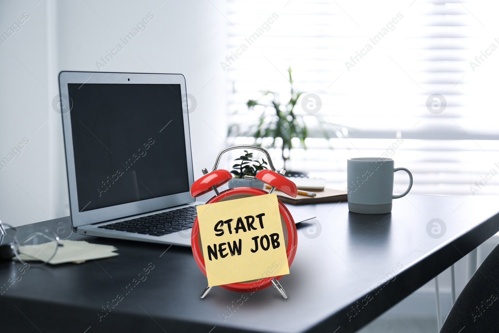 Image of Sticker with text Start New Job on alarm clock near laptop in modern office